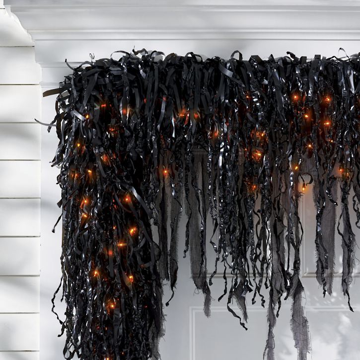 Pre-lit drippy garland glowing at night with Halloween decorations