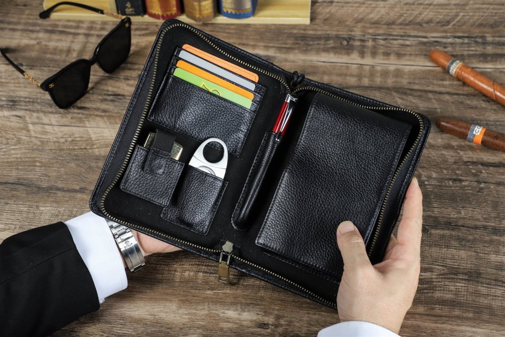 Hands opening the zip-around black leather cigar organizer