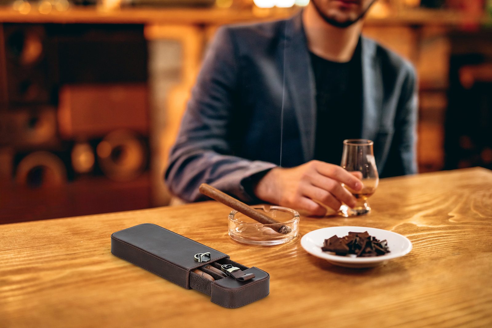 Man with a cigar at a bar table beside the CF5018 leather case with its tray partly open