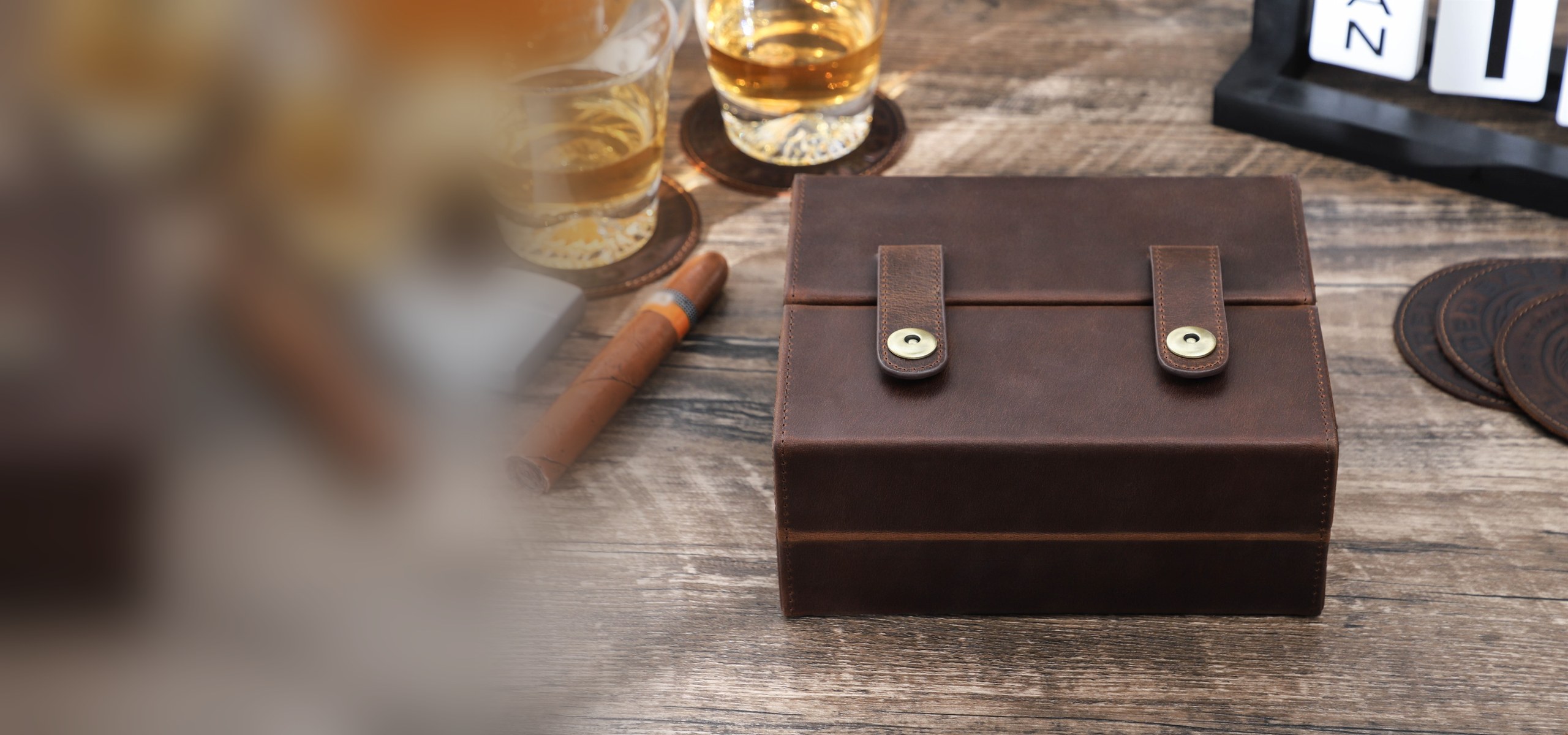 CF5029 7-cigar double-open leather cigar box closed on a wooden table beside whisky glasses and a cigar