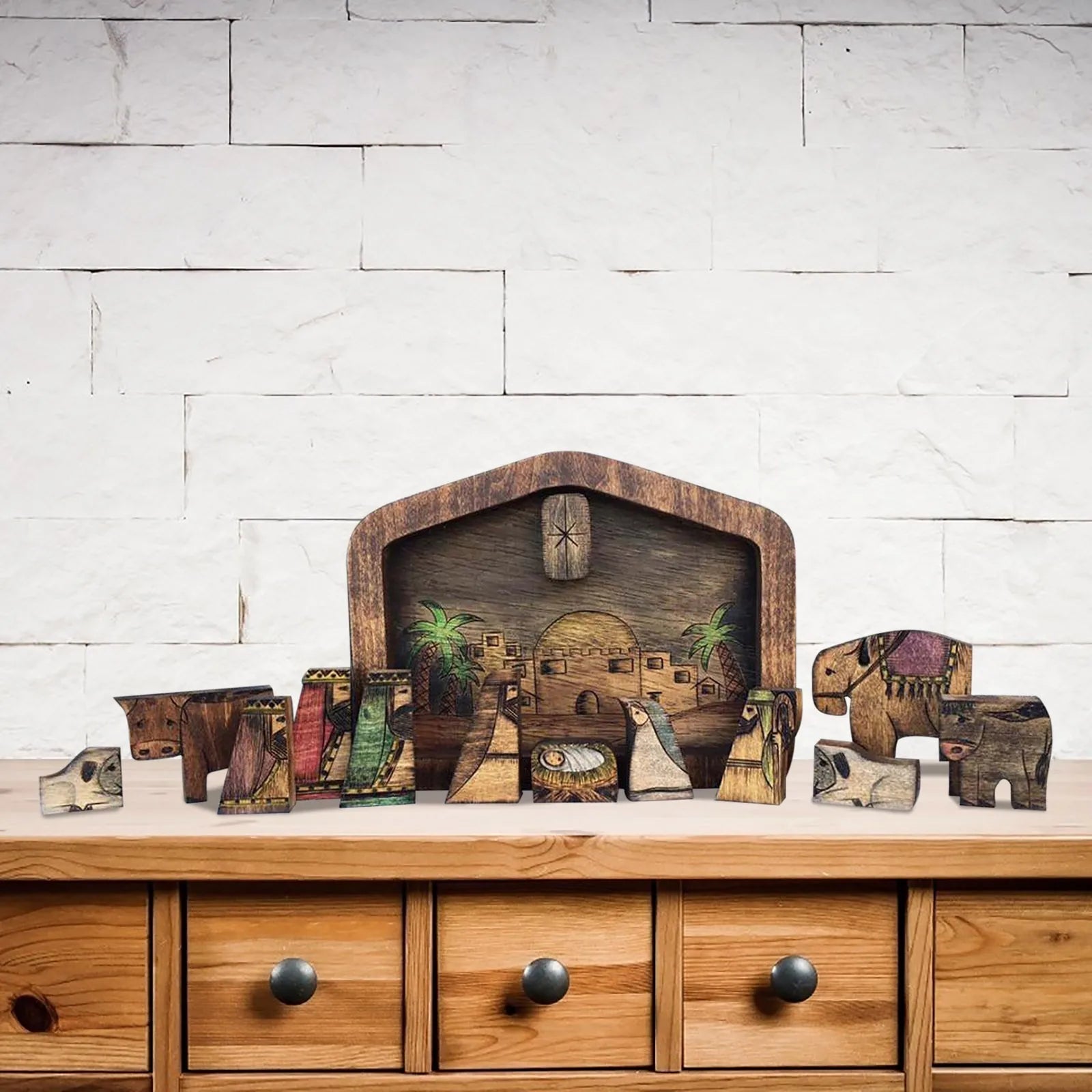 Handcrafted wooden nativity scene puzzle displayed on a wooden cabinet top.