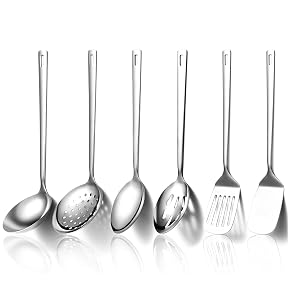 Seis utensilios de cocina de acero inoxidable que se muestran en fila: cucharón para sopa, cuchara ranurada, cuchara sólida, cuchara desnatadora, rallador y espátula sobre fondo blanco con reflejos.