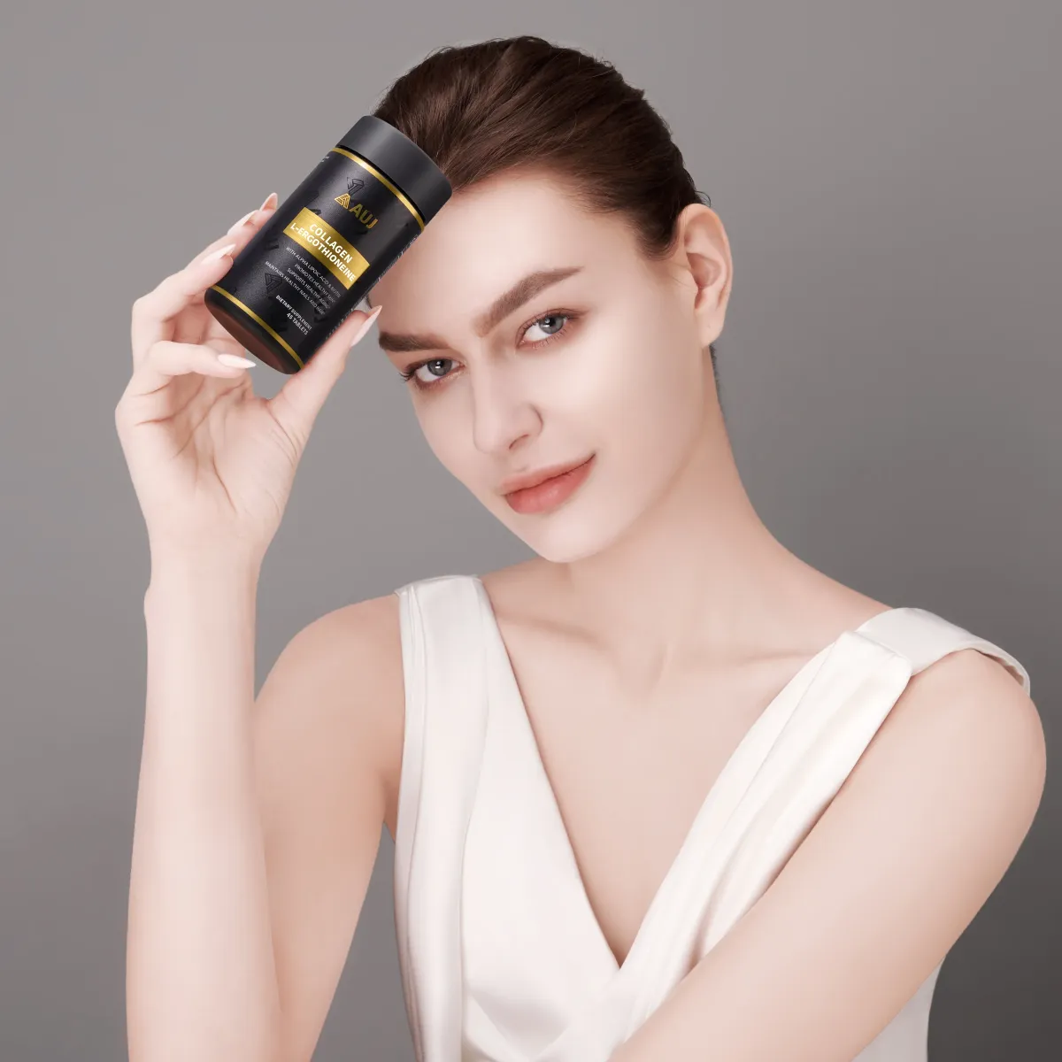 Woman holding an AUJ bottle beside her face
