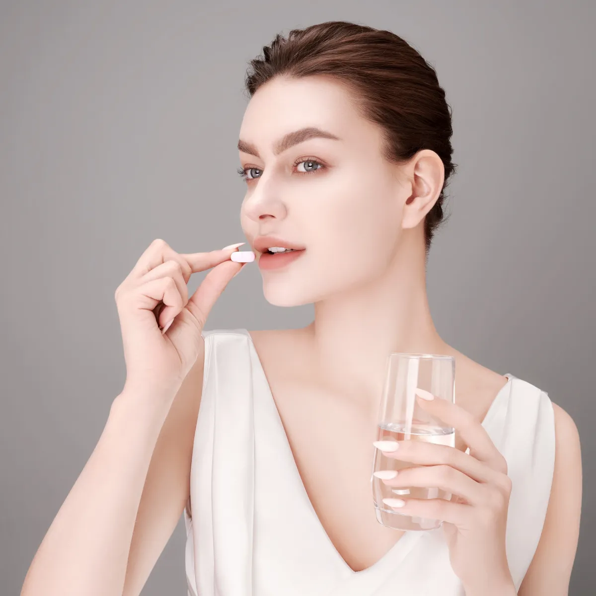 Woman taking a tablet with a glass of water