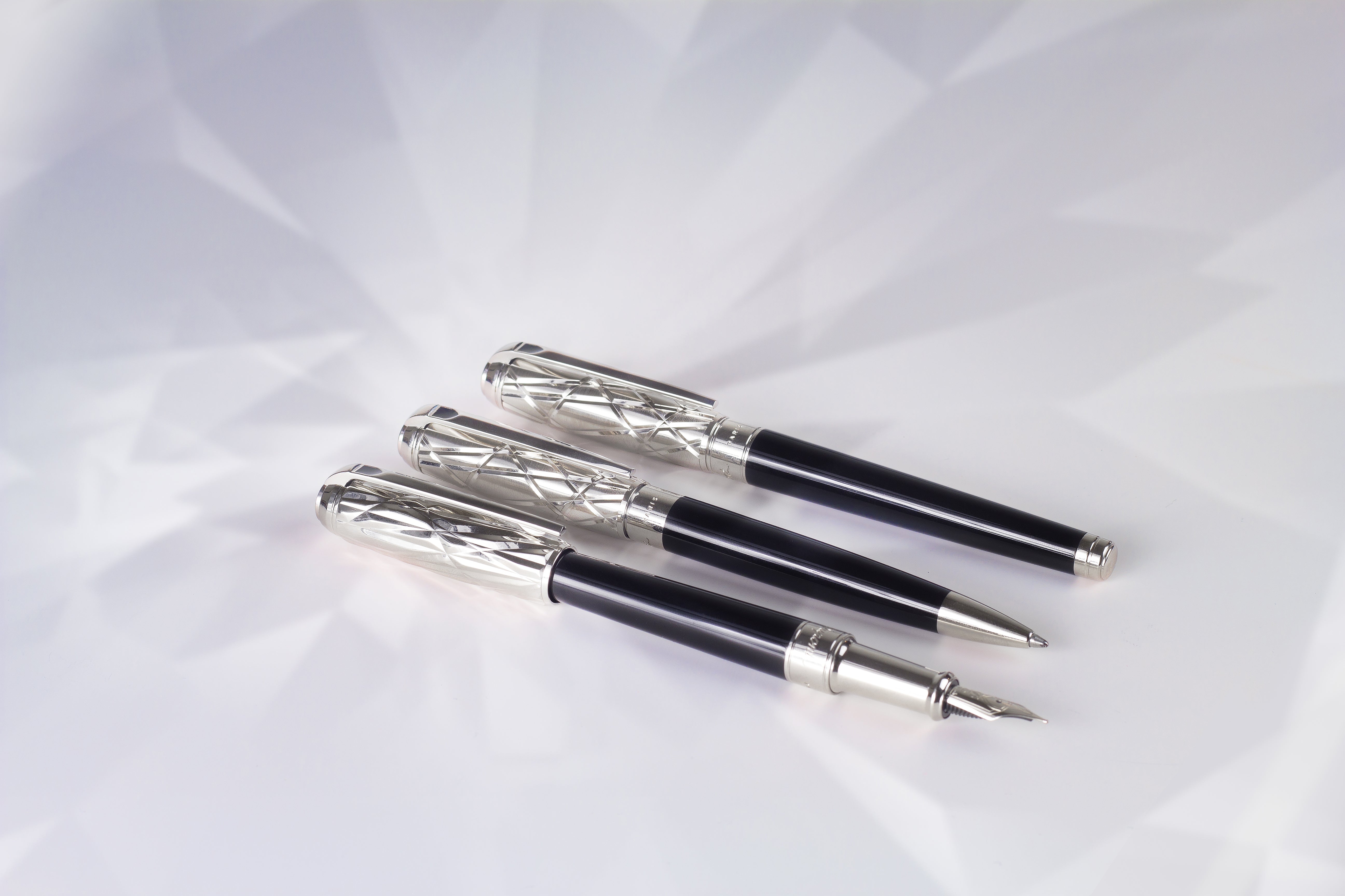 S.T. Dupont Line d fountain, roller and ballpoint pens with black lacquer and fire head guilloche on white background