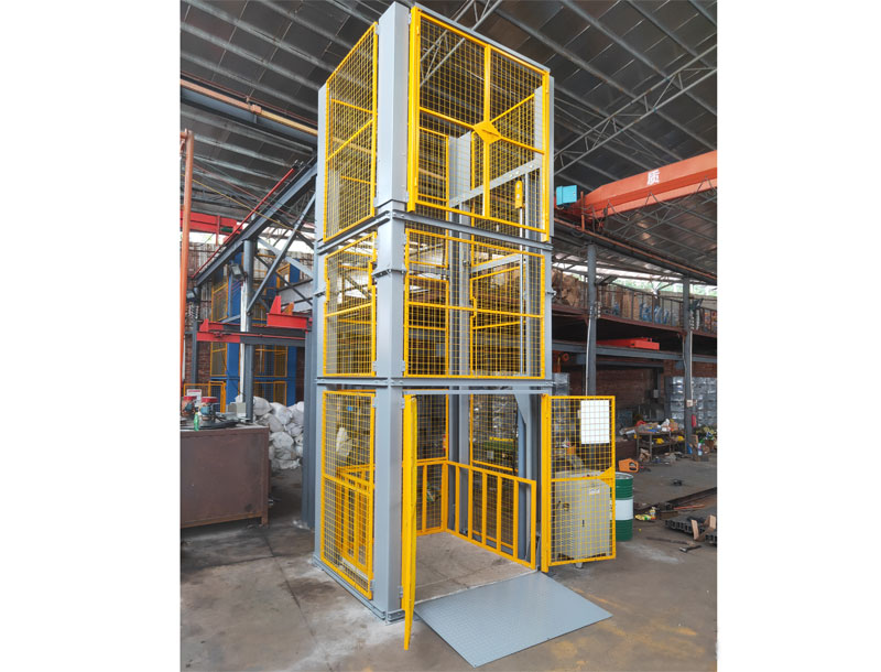 Hydraulic cargo lift with safety mesh enclosure for vertical material handling in industrial warehouse