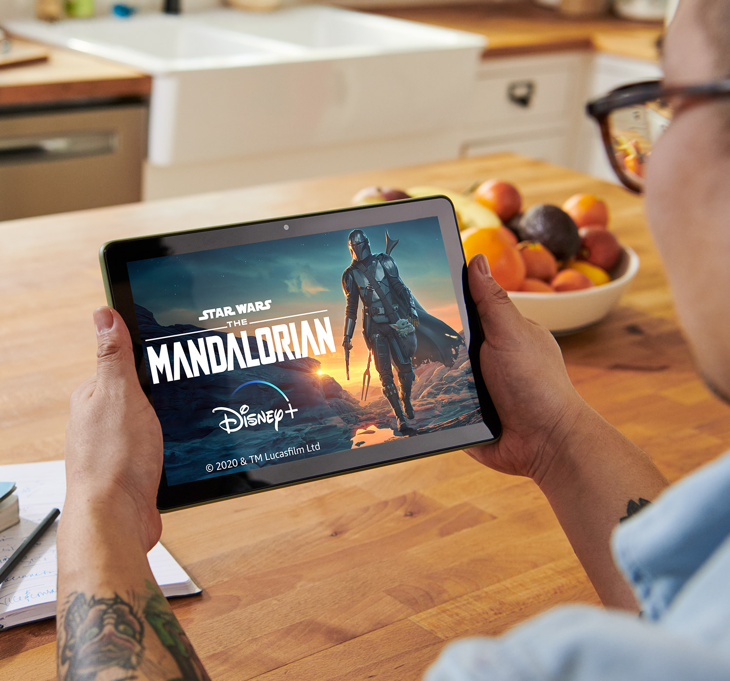 Un hombre mira The Mandalorian en su tableta Fire HD 10 mientras está sentado en la cocina.