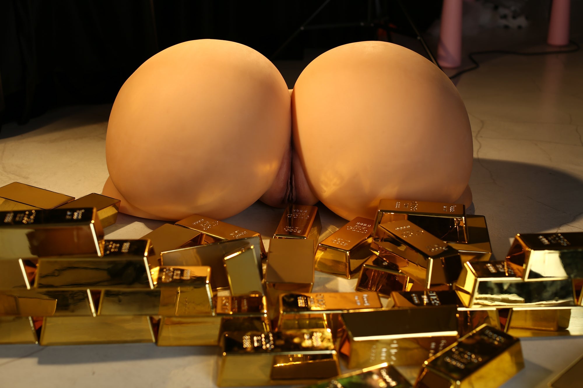 Realistic silicone sex doll torso with large buttocks surrounded by multiple gold bars, emphasizing the attractive and luxurious design.