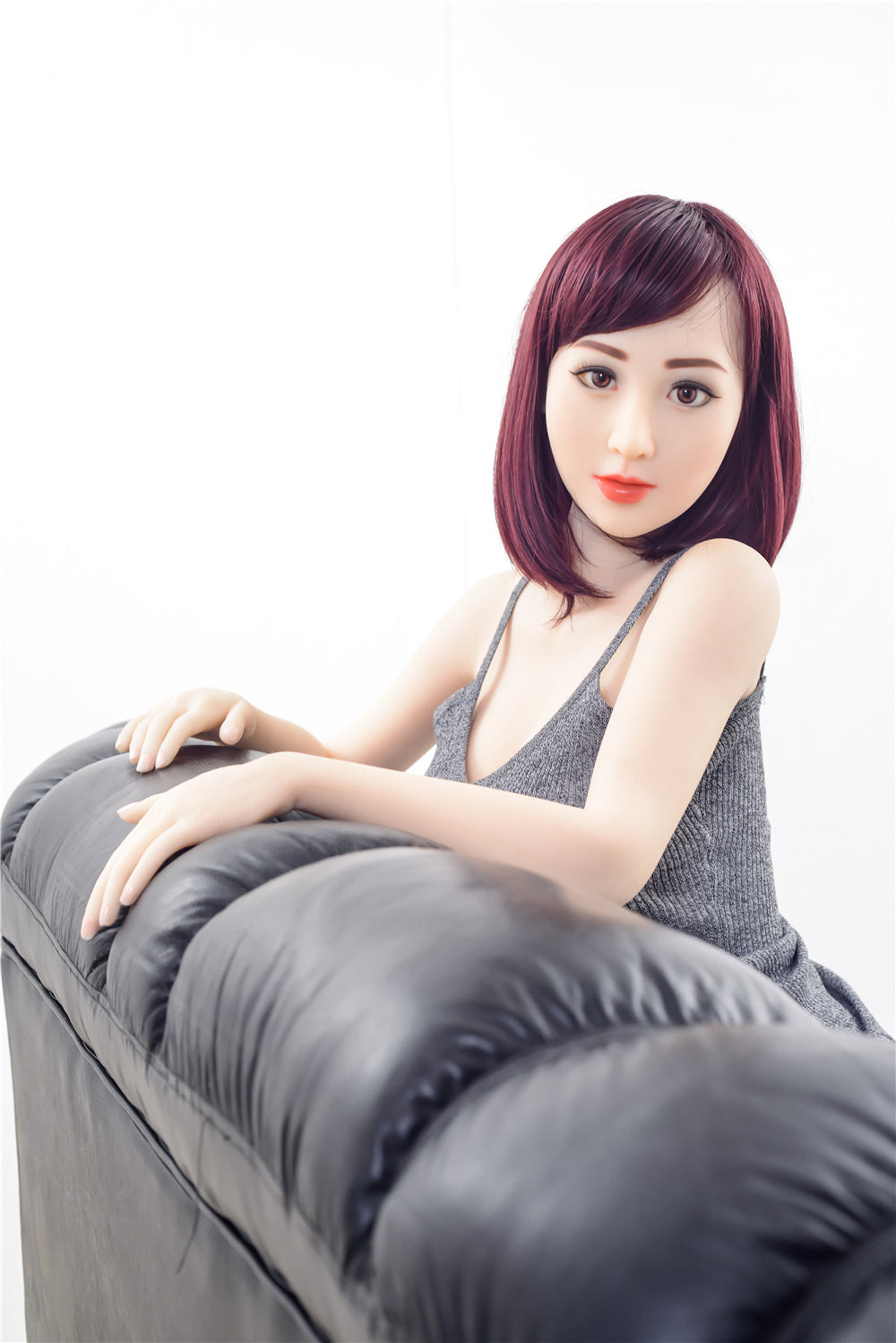 Jennifer TPE sex doll with red hair sitting on black leather sofa
