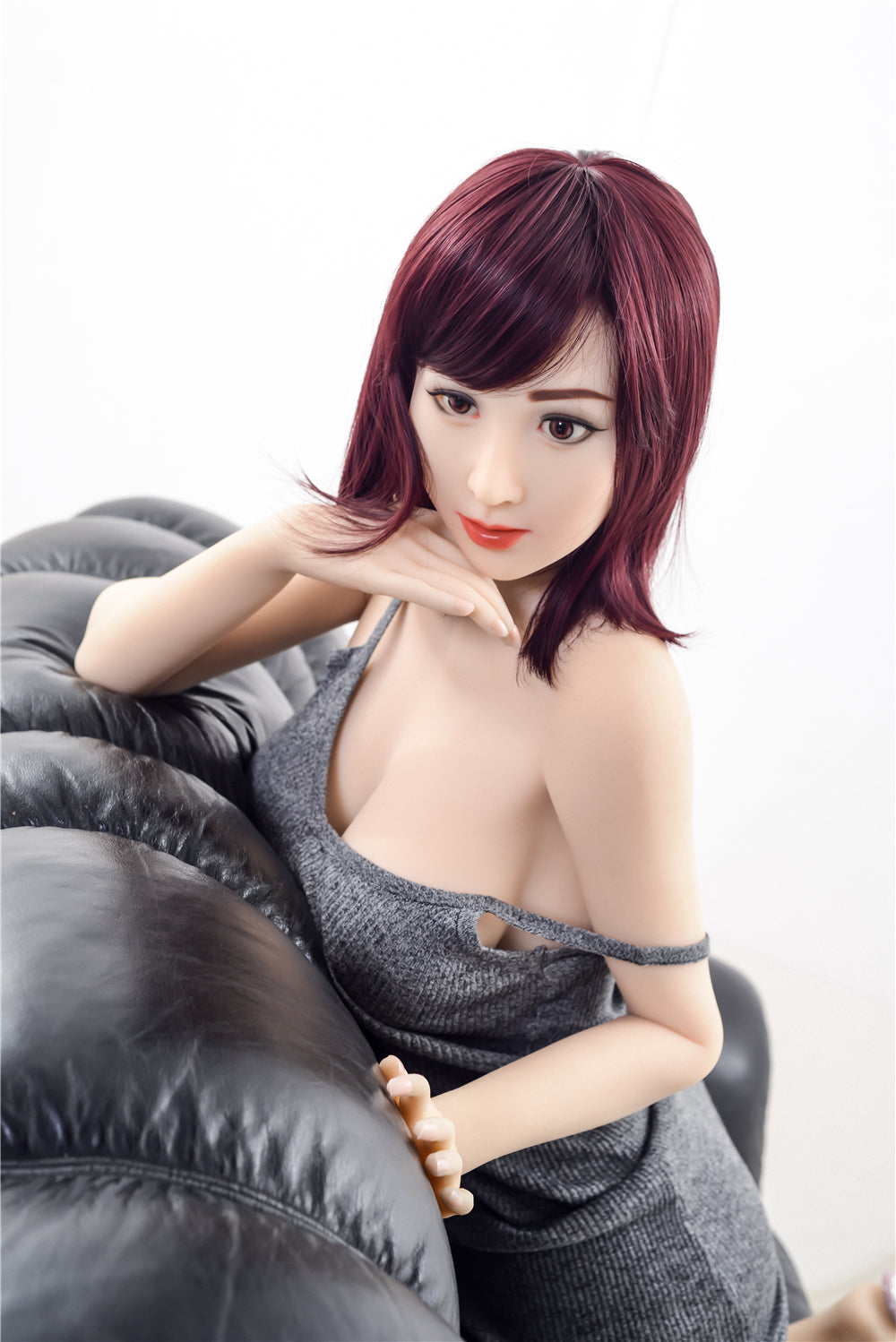 160cm TPE Sex Doll Jennifer resting on black leather sofa, looking up