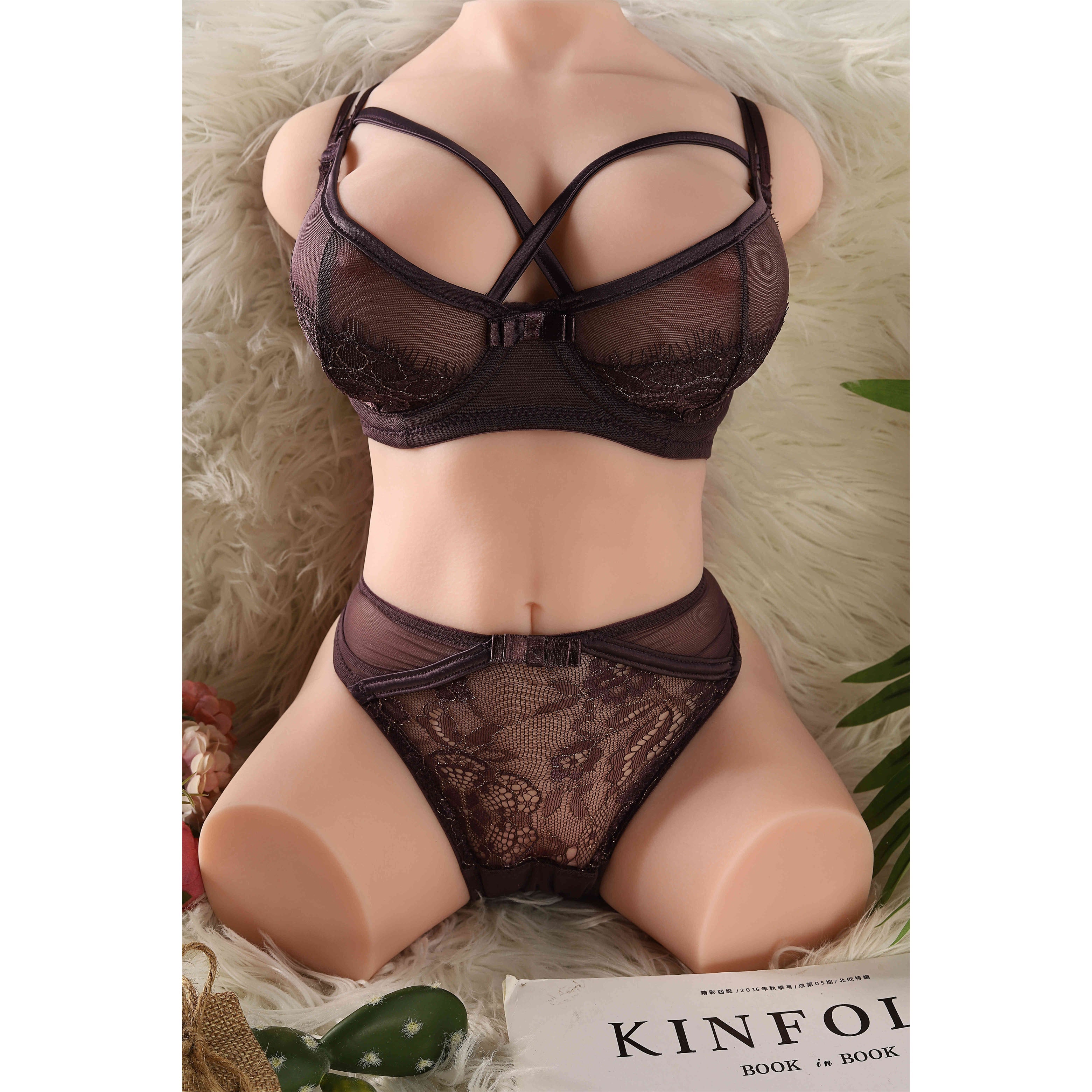 Realistic life-size sex doll torso in black lace lingerie on a soft white surface with Kinfolk magazine and cactus decor