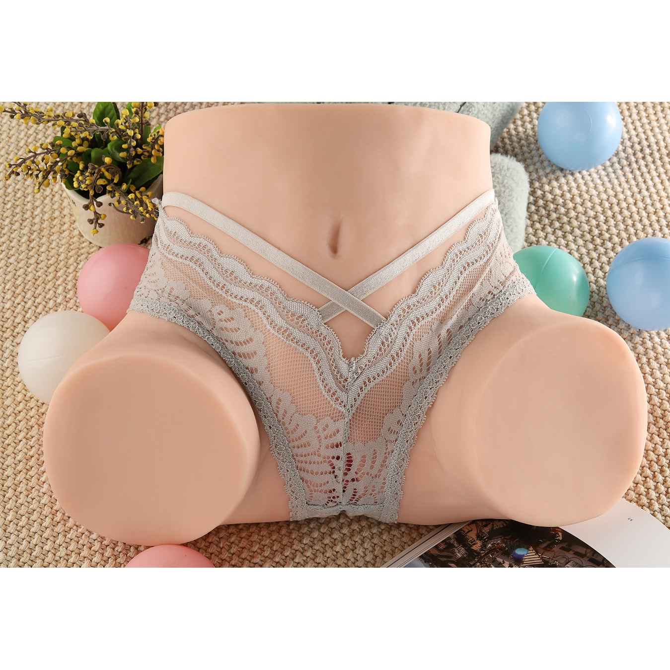 Realistic life-size male masturbator big ass torso sex doll wearing grey lace lingerie, surrounded by colorful balls and a plant in the background.