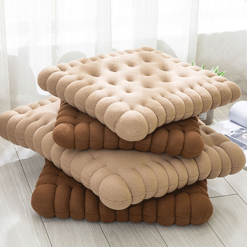 Four biscuit shaped dog cushion beds stacked together from the bottom up on the floor. Two are brown and two are khaki.