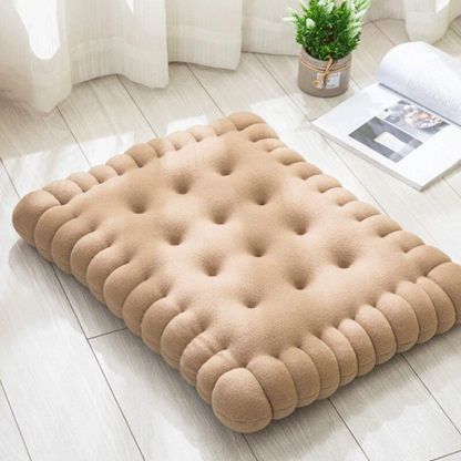 A khaki biscuit shaped dog cushion bed on the floor.