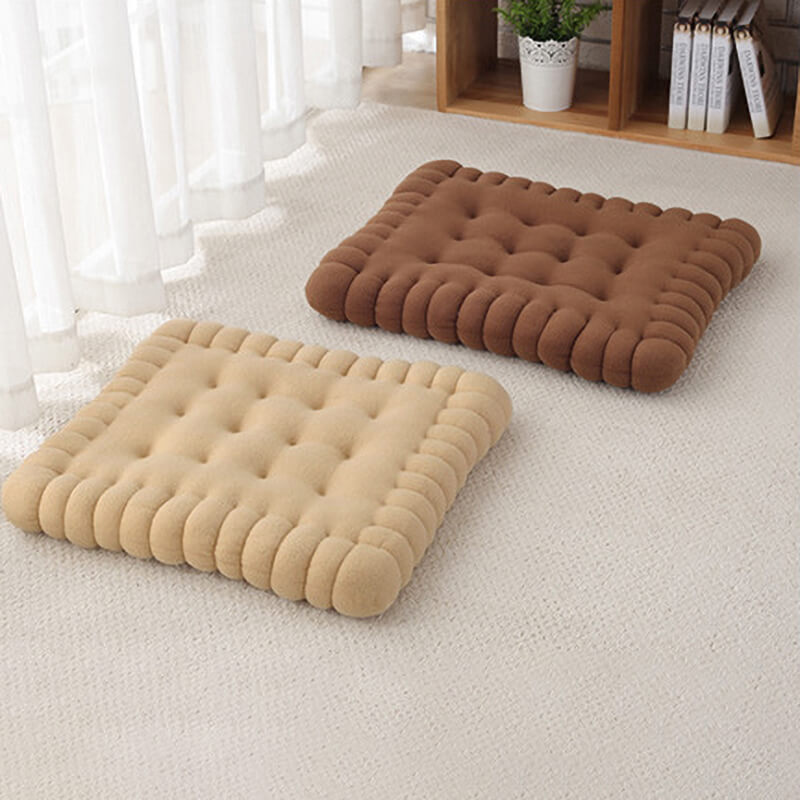 Two biscuit shaped dog cushion beds on the floor, one is brown on the top right, and one is khaki on the bottom left.