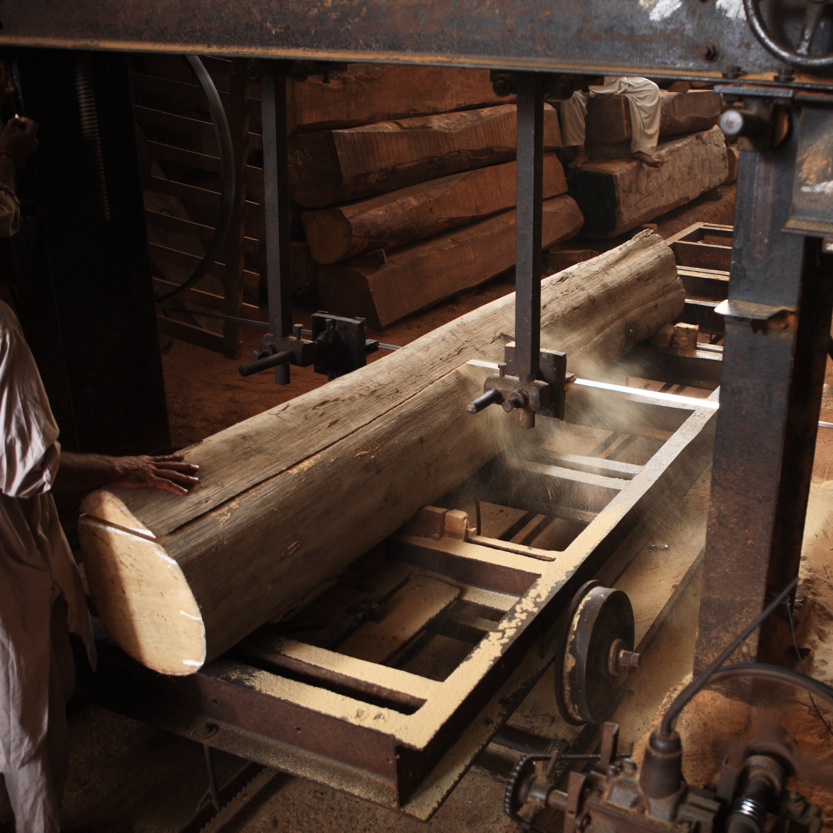 Workers sawing Burmese teak with a band saw at a factory in Myanmar