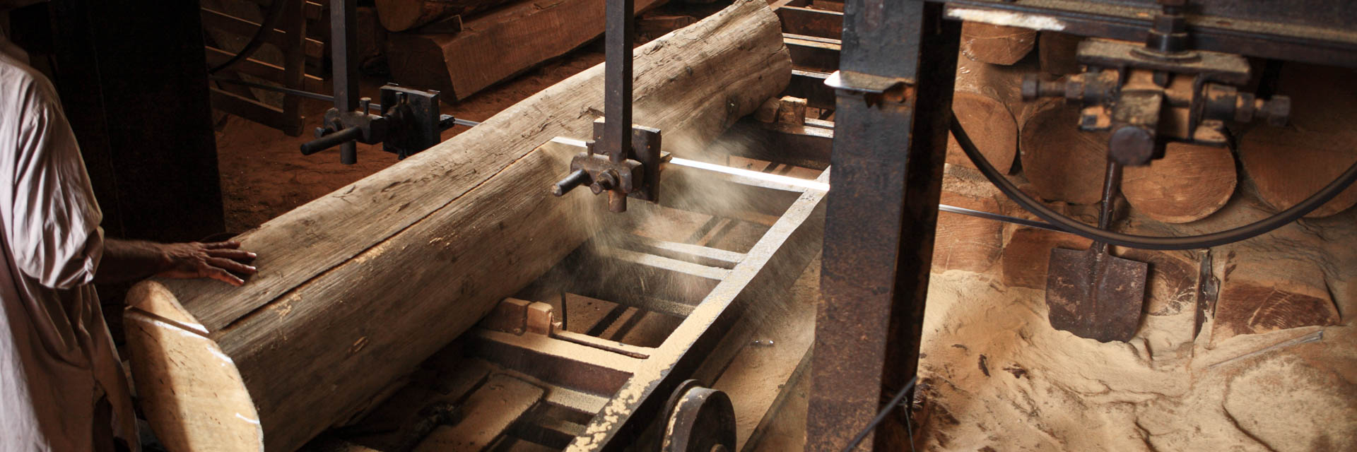 Workers sawing Burmese teak with a band saw at a factory in Myanmar