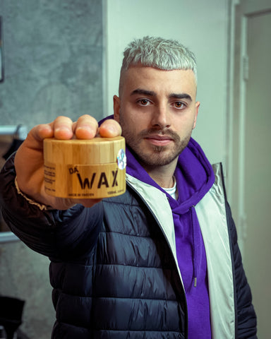 Man with dyed French-crop in purple jacket, holding a stronghold hairstyling wax