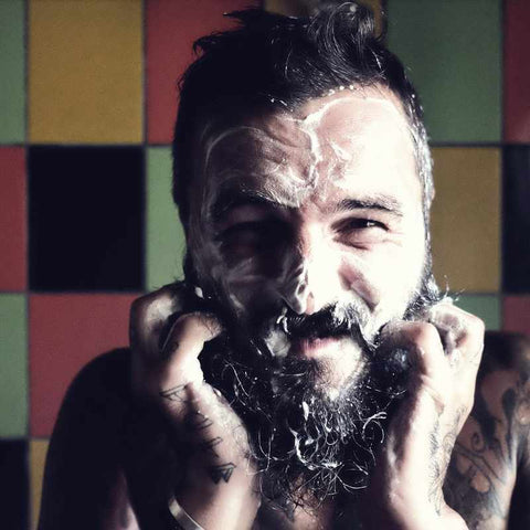 Tattooed bearded man using a face-wash