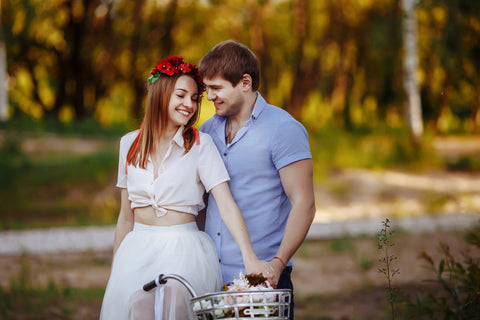 Happy couple holding a bike in the woods