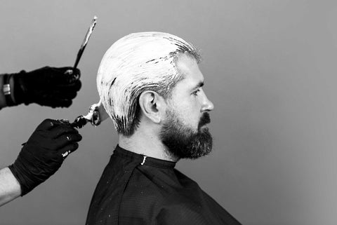 Fashionable bearded man getting hair dyed at a stylist's