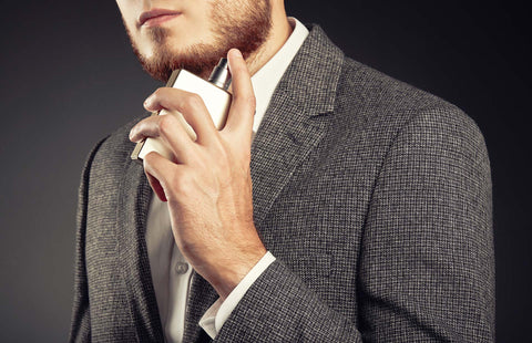 Young attractive man in suit spraying a cologne
