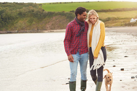 Happy couple walking their dog by the beach