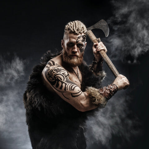 Viking man with long beard and textured hair holding an axe - rugged beard style inspiration